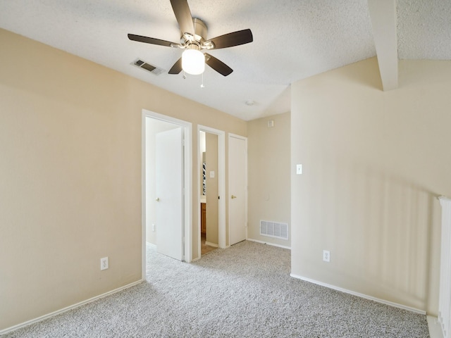 carpeted empty room with ceiling fan, a textured ceiling, and beamed ceiling