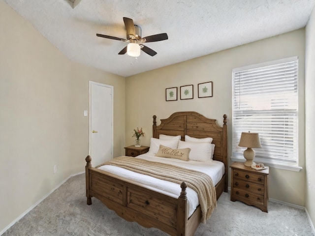 carpeted bedroom featuring ceiling fan and a textured ceiling