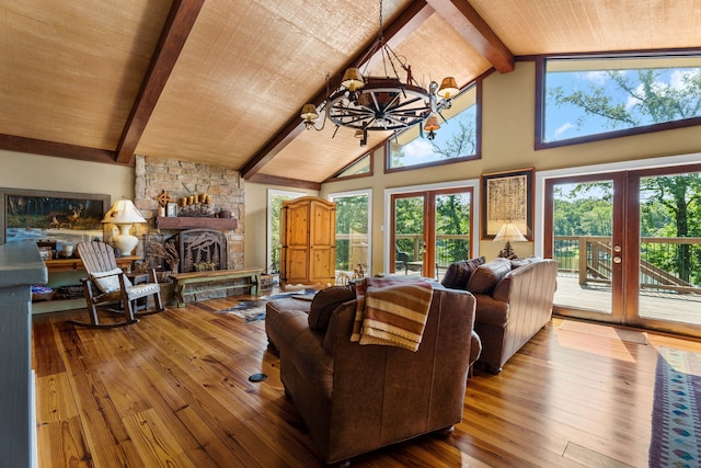 living room featuring beam ceiling, a stone fireplace, high vaulted ceiling, french doors, and a chandelier