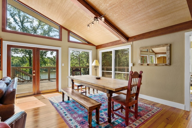 dining room featuring lofted ceiling with beams, french doors, and light wood-type flooring