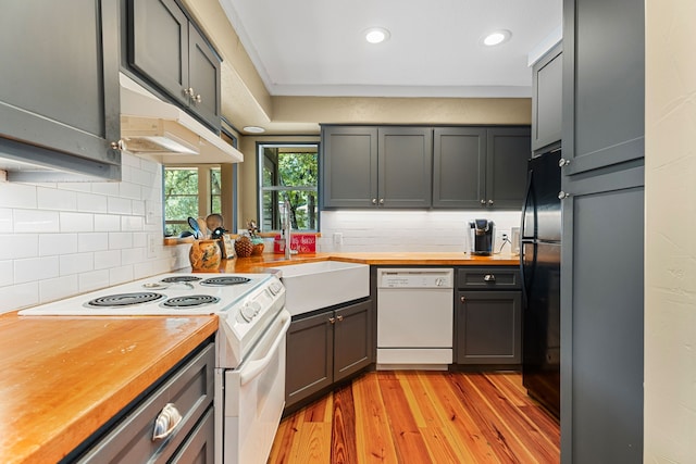 kitchen with sink, white appliances, wooden counters, and light wood-type flooring