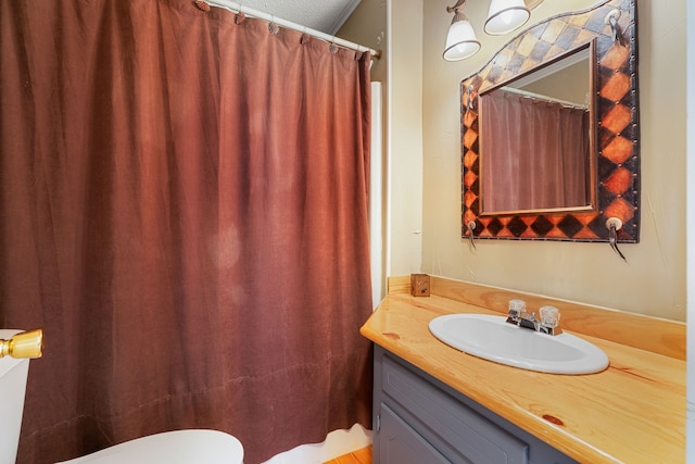 bathroom featuring a textured ceiling, toilet, and vanity