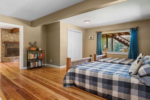 bedroom with a closet, a fireplace, and light hardwood / wood-style flooring