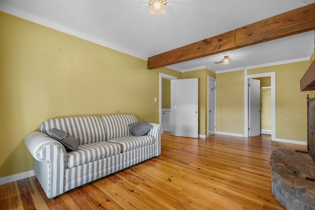 living room featuring beamed ceiling, crown molding, and hardwood / wood-style flooring