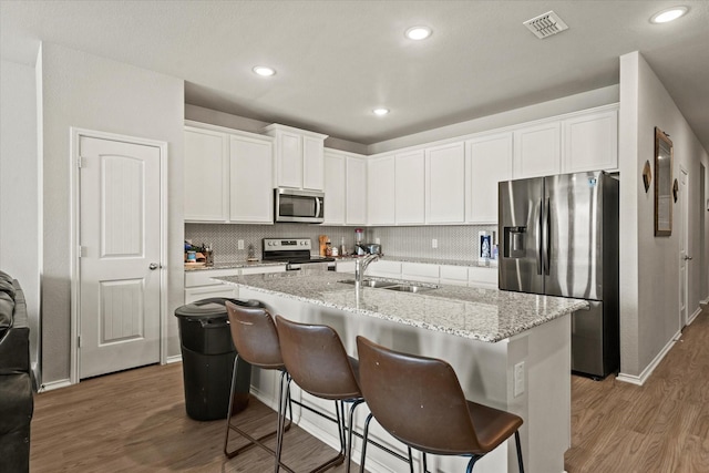 kitchen featuring a center island with sink, sink, stainless steel appliances, white cabinets, and dark hardwood / wood-style flooring