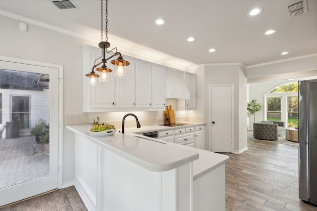 kitchen featuring light countertops, hanging light fixtures, visible vents, freestanding refrigerator, and white cabinets