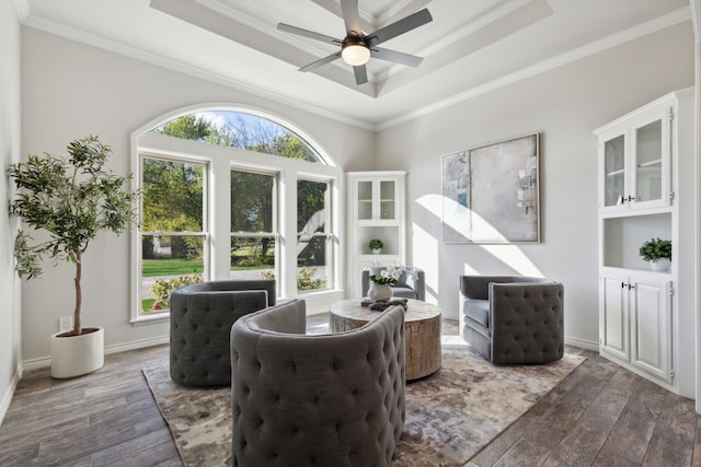 sitting room with ornamental molding, ceiling fan, a tray ceiling, and dark wood-style flooring