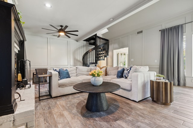 living area with visible vents, stairway, ornamental molding, wood finished floors, and a decorative wall