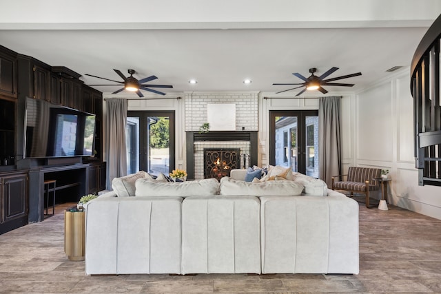 living area with ceiling fan, plenty of natural light, a fireplace, and a decorative wall