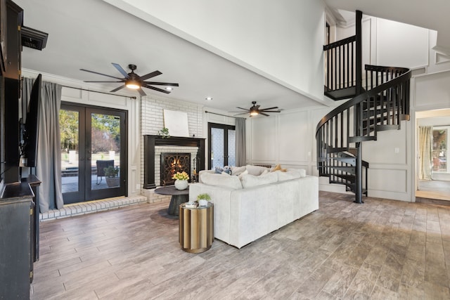 living area featuring a healthy amount of sunlight, stairs, a decorative wall, and french doors