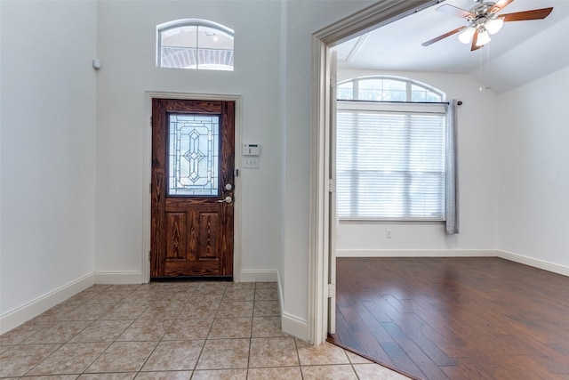 foyer entrance featuring ceiling fan, light tile patterned floors, lofted ceiling, and a healthy amount of sunlight