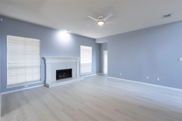 unfurnished living room with ceiling fan, a fireplace, and light hardwood / wood-style flooring