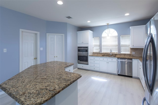 kitchen with white cabinets, appliances with stainless steel finishes, sink, and a kitchen island