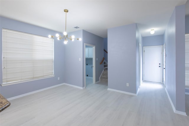 empty room featuring a chandelier and light hardwood / wood-style flooring