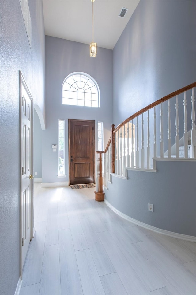 entryway with light hardwood / wood-style floors and a towering ceiling