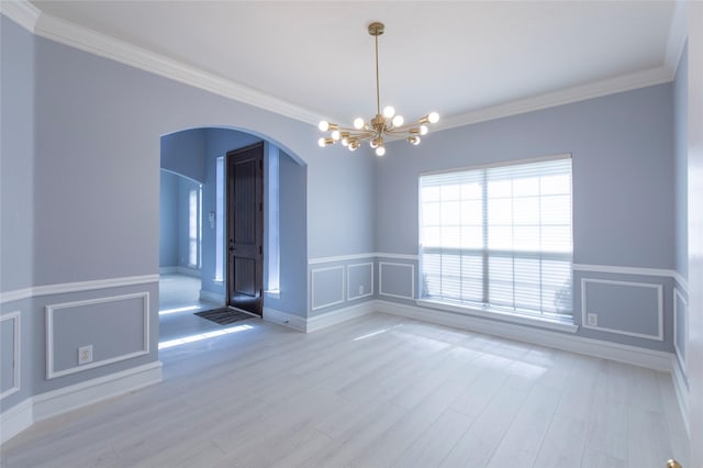 empty room featuring ornamental molding, a healthy amount of sunlight, and a notable chandelier