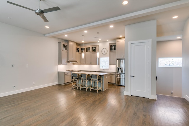 kitchen featuring pendant lighting, a center island, a kitchen bar, sink, and stainless steel fridge