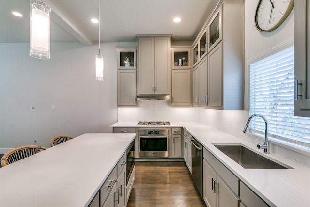 kitchen featuring pendant lighting, dark wood-type flooring, stainless steel appliances, sink, and gray cabinets