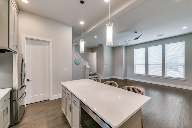 kitchen featuring ceiling fan, appliances with stainless steel finishes, decorative light fixtures, white cabinets, and a center island