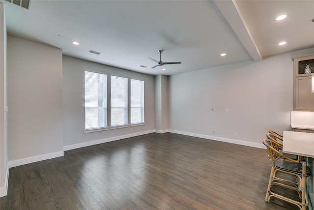 unfurnished living room featuring ceiling fan, dark hardwood / wood-style floors, and beamed ceiling