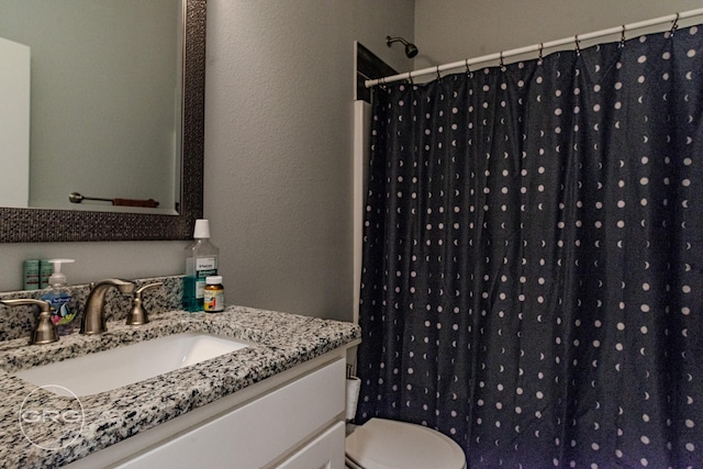 bathroom featuring toilet, vanity, and a shower with shower curtain