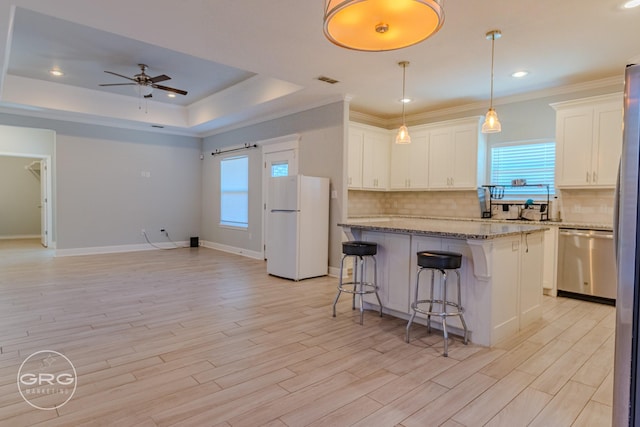 kitchen featuring white cabinets, dishwasher, white refrigerator, light stone counters, and a tray ceiling