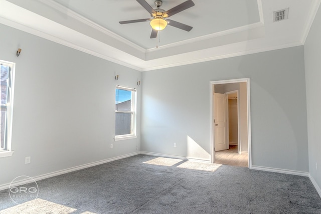 carpeted spare room with ceiling fan, a tray ceiling, and ornamental molding