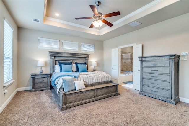 carpeted bedroom with a tray ceiling, ensuite bathroom, crown molding, and ceiling fan