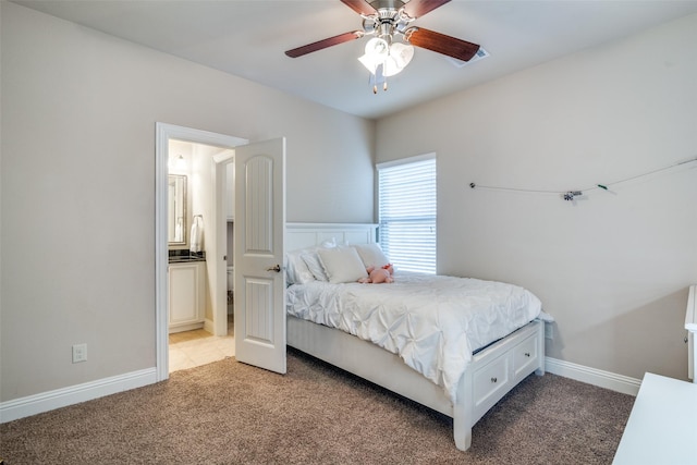 bedroom featuring ceiling fan, light colored carpet, and ensuite bathroom