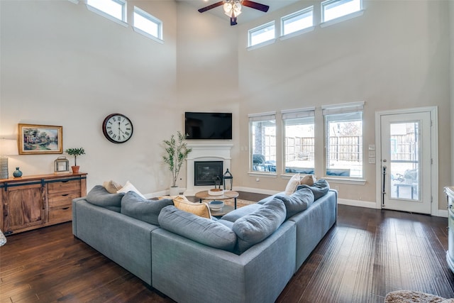 living room with dark wood-type flooring, a high ceiling, and ceiling fan