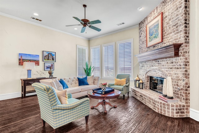 living room featuring ceiling fan, ornamental molding, a fireplace, and dark hardwood / wood-style floors