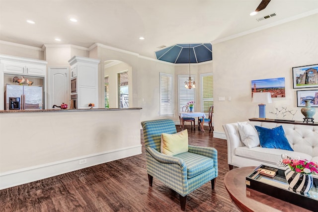 living room with dark hardwood / wood-style flooring, ornamental molding, and a notable chandelier