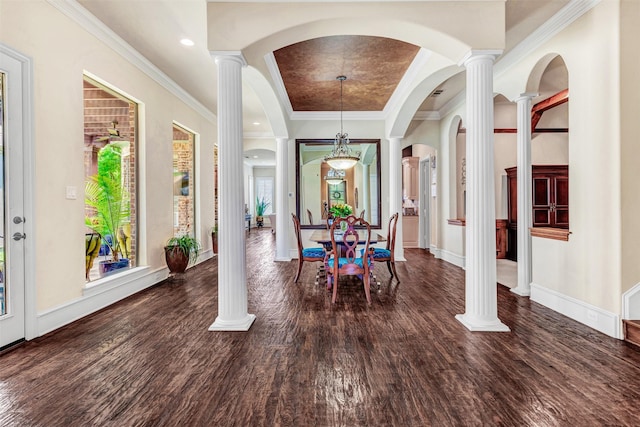 dining area featuring dark wood-type flooring, ornate columns, crown molding, and a raised ceiling