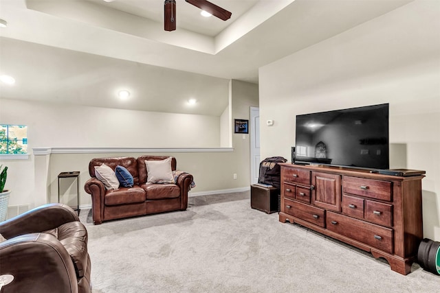 living room with ceiling fan, a raised ceiling, and light carpet