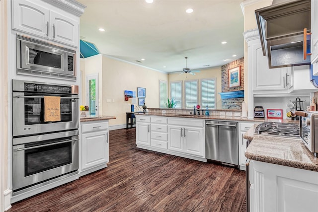 kitchen featuring white cabinetry, kitchen peninsula, ceiling fan, appliances with stainless steel finishes, and dark wood-type flooring