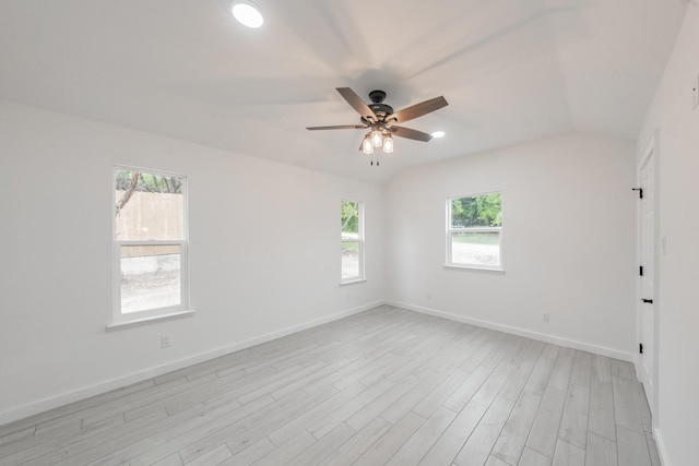 empty room with light hardwood / wood-style flooring, a healthy amount of sunlight, and vaulted ceiling