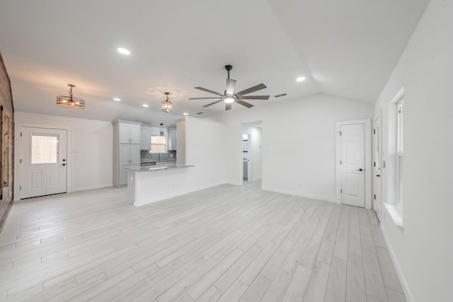 unfurnished living room featuring lofted ceiling, ceiling fan, and light hardwood / wood-style flooring