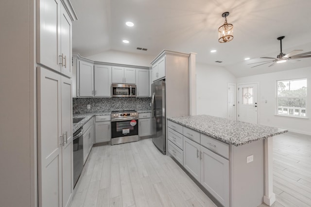 kitchen with lofted ceiling, backsplash, gray cabinetry, and stainless steel appliances