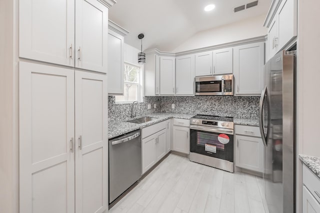 kitchen with light stone countertops, appliances with stainless steel finishes, sink, backsplash, and hanging light fixtures