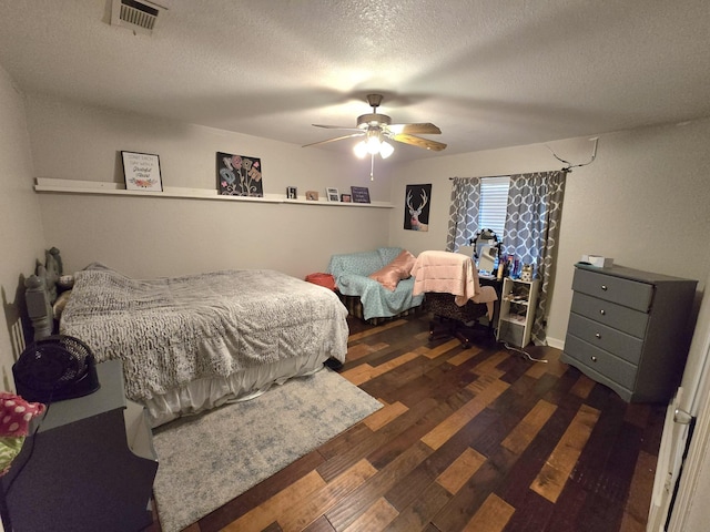 bedroom with ceiling fan, dark wood-type flooring, and a textured ceiling