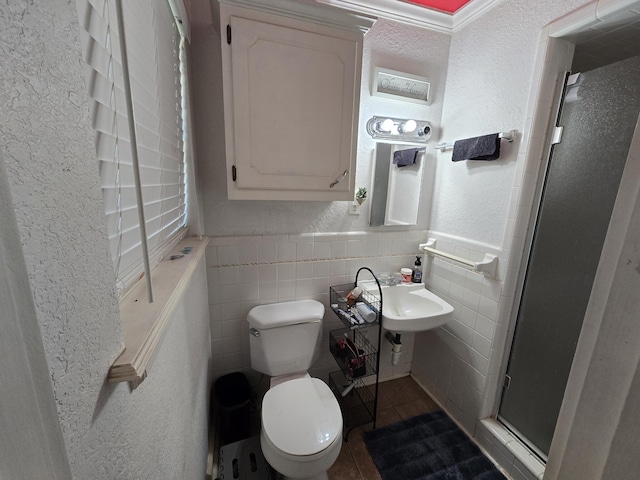 bathroom with toilet, tile patterned flooring, tile walls, and a shower with door