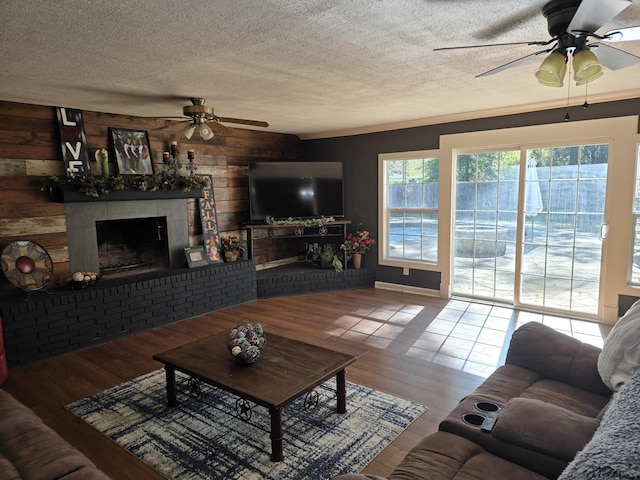 living room with ceiling fan, wood-type flooring, and wood walls