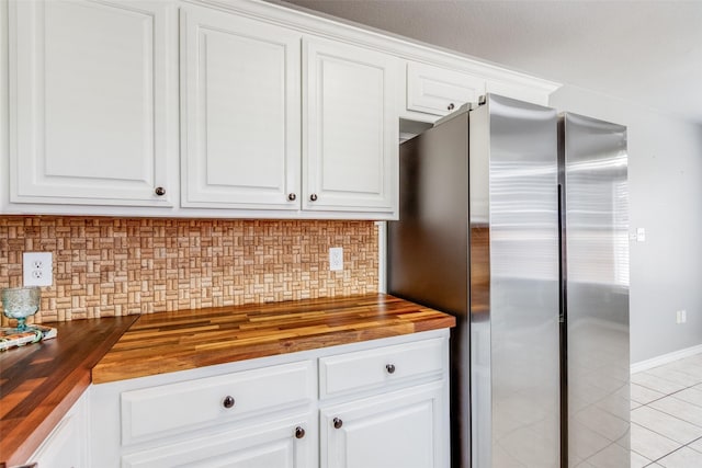 kitchen featuring stainless steel refrigerator, white cabinets, and wood counters