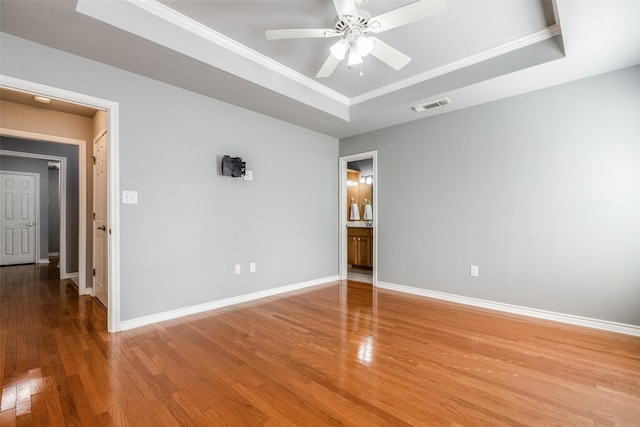 spare room featuring hardwood / wood-style flooring, ornamental molding, a raised ceiling, and ceiling fan