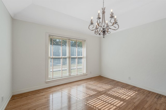 empty room with an inviting chandelier, ornamental molding, hardwood / wood-style flooring, and a tray ceiling