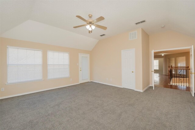 carpeted spare room featuring vaulted ceiling, ceiling fan, and a textured ceiling