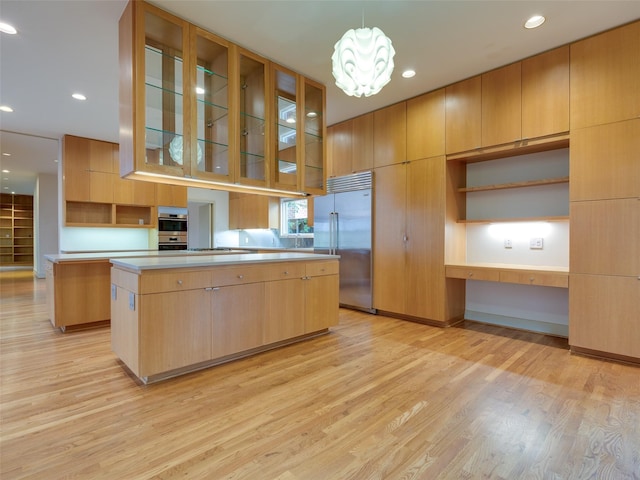 kitchen with stainless steel appliances, light hardwood / wood-style flooring, a kitchen island, and decorative light fixtures