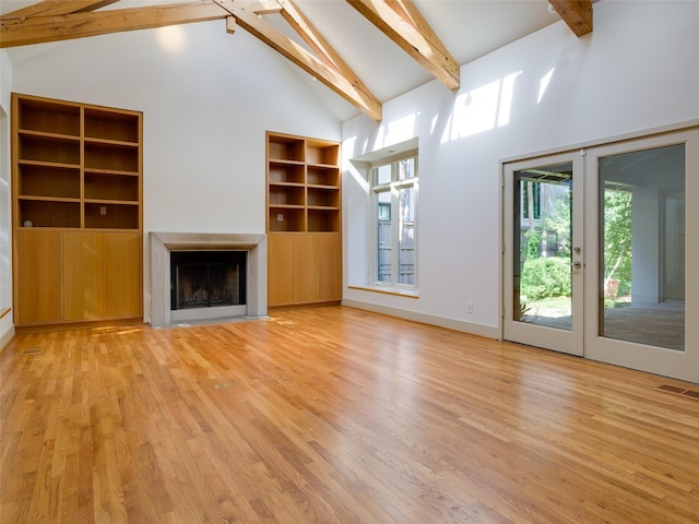 unfurnished living room with high vaulted ceiling, beamed ceiling, french doors, and light wood-type flooring