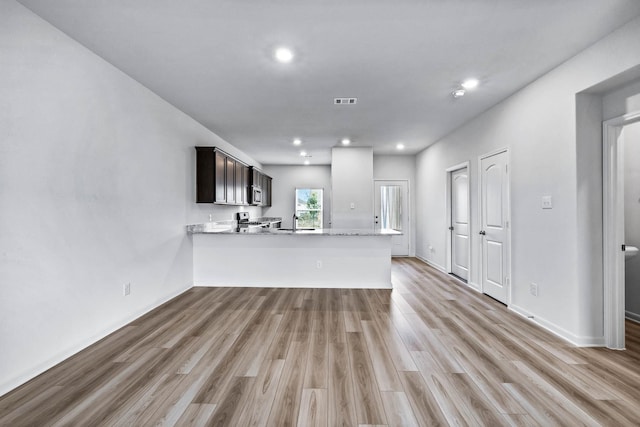 kitchen with sink, kitchen peninsula, light hardwood / wood-style flooring, dark brown cabinets, and stove