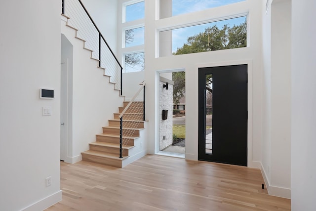 entryway featuring a towering ceiling and light hardwood / wood-style floors